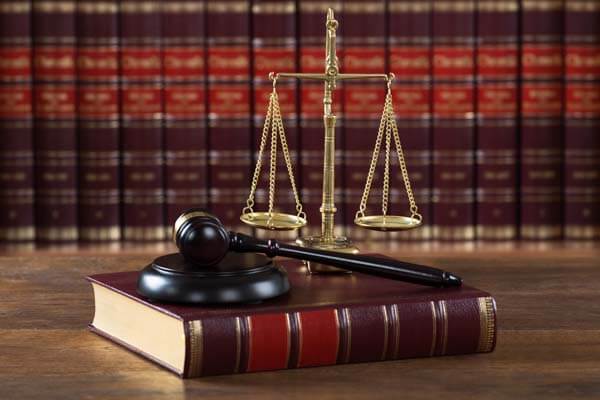 Closeup of mallet and legal book with justice scale on table in courtroom